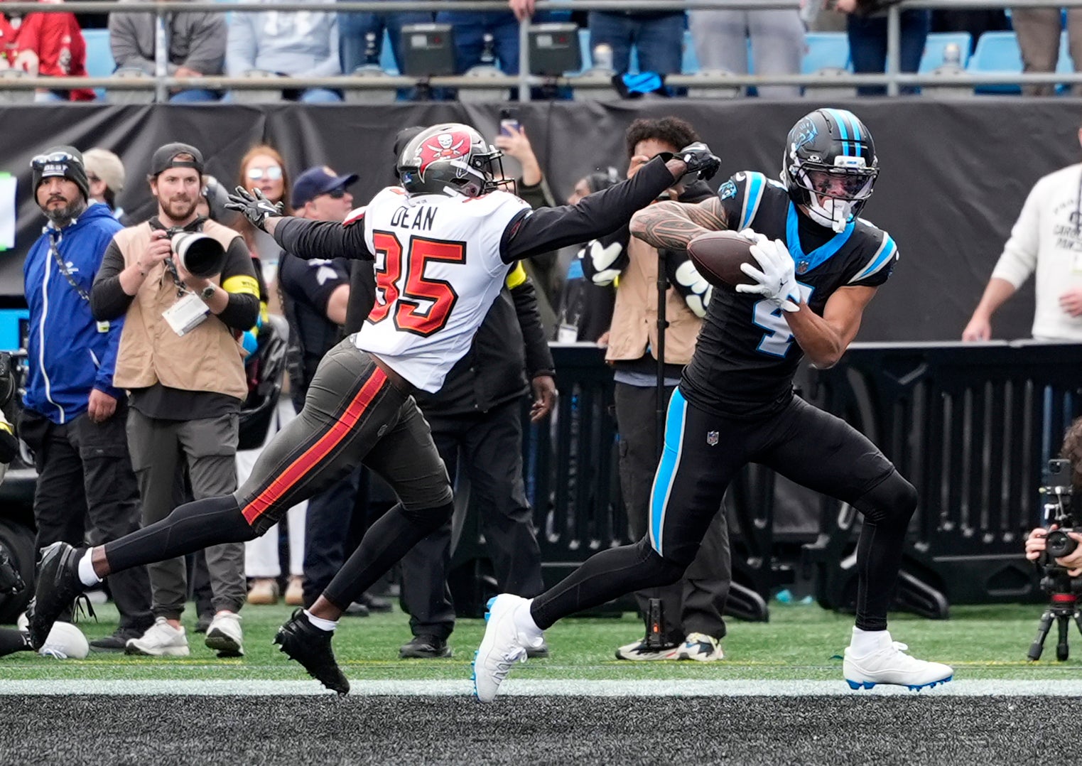 Dec 21, 2025; Charlotte, North Carolina, USA; Carolina Panthers wide receiver Tetairoa McMillan (4) catches a touchdown against Tampa Bay Buccaneers cornerback Jamel Dean (35) during the first half at Bank of America Stadium.