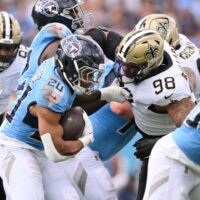 Dec 28, 2025; Nashville, Tennessee, USA; Tennessee Titans running back Tony Pollard (20) runs the ball against New Orleans Saints defensive end Jonathan Bullard (98) during the first quarter of the game at Nissan Stadium.