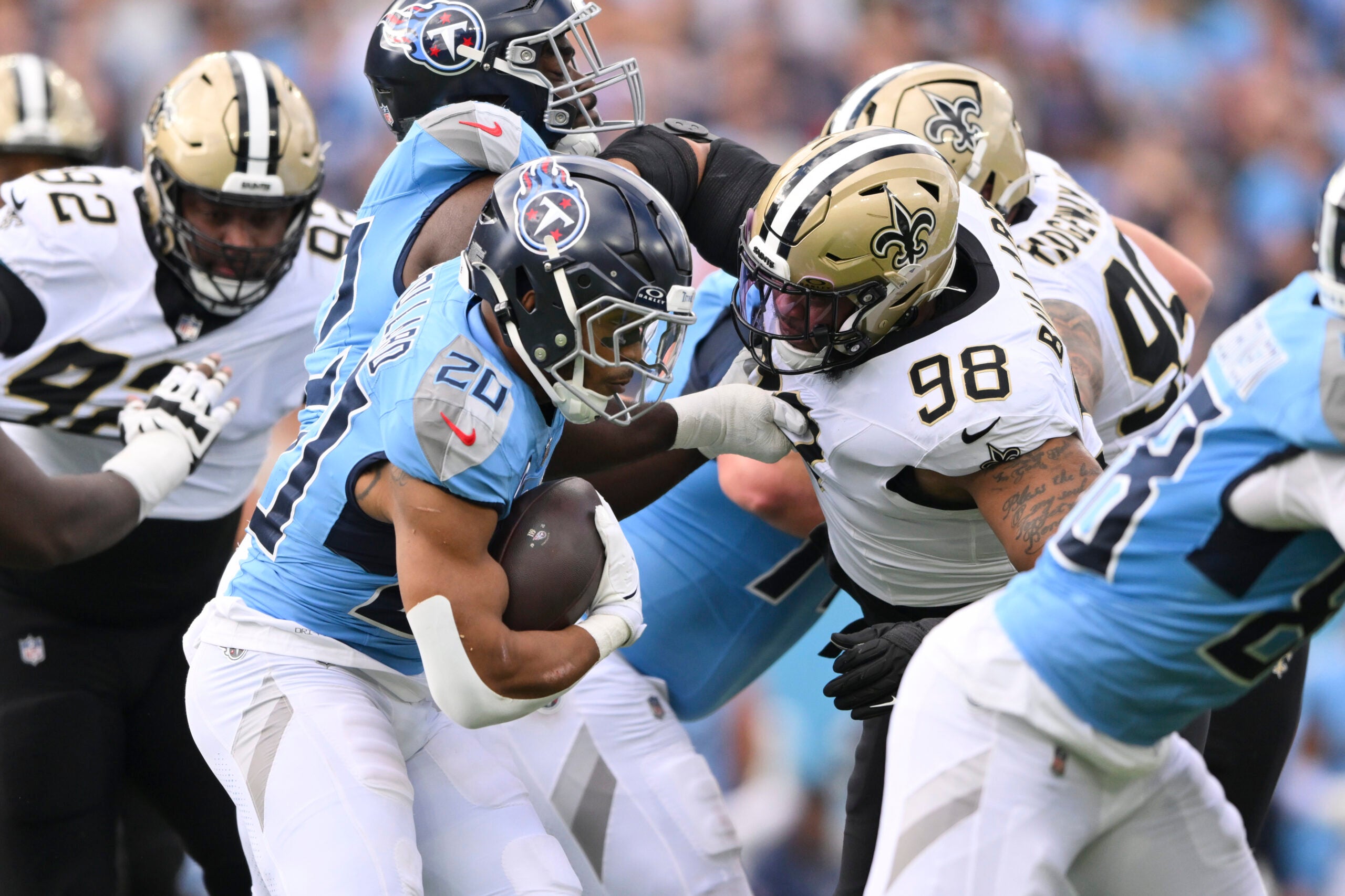 Dec 28, 2025; Nashville, Tennessee, USA; Tennessee Titans running back Tony Pollard (20) runs the ball against New Orleans Saints defensive end Jonathan Bullard (98) during the first quarter of the game at Nissan Stadium.