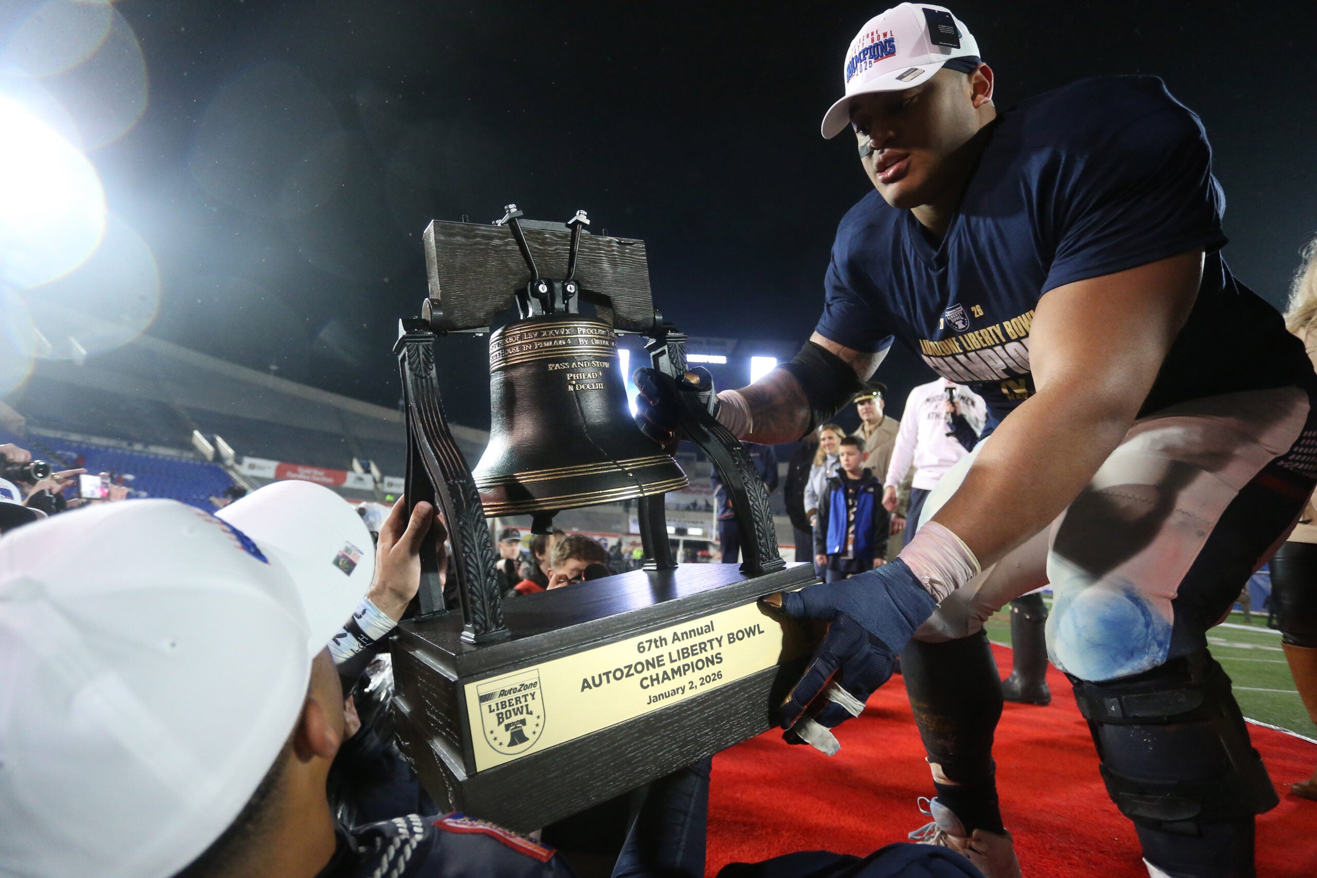 Jan 2, 2026; Memphis, TN, USA; Navy Midshipmen defensive lineman Landon Robinson (96) passes the Liberty Bell trophy off the stage after defeating the Cincinnati Bearcats in the Liberty Bowl at Simmons Bank Liberty Stadium.
