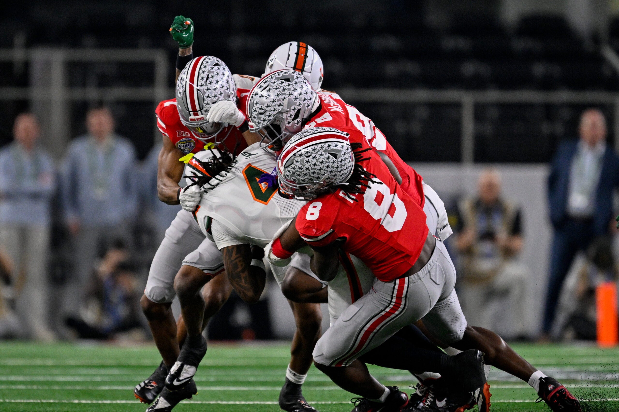 Dec 31, 2025; Arlington, TX, USA; Ohio State Buckeyes linebacker Arvell Reese (8) and defensive lineman Kayden McDonald (98) and cornerback Davison Igbinosun (1) tackles Miami Hurricanes running back Mark Fletcher Jr. (4) during the 2025 Cotton Bowl and quarterfinal game of the College Football Playoff at AT&T Stadium. Mandatory Credit: Jerome Miron-Imagn Images