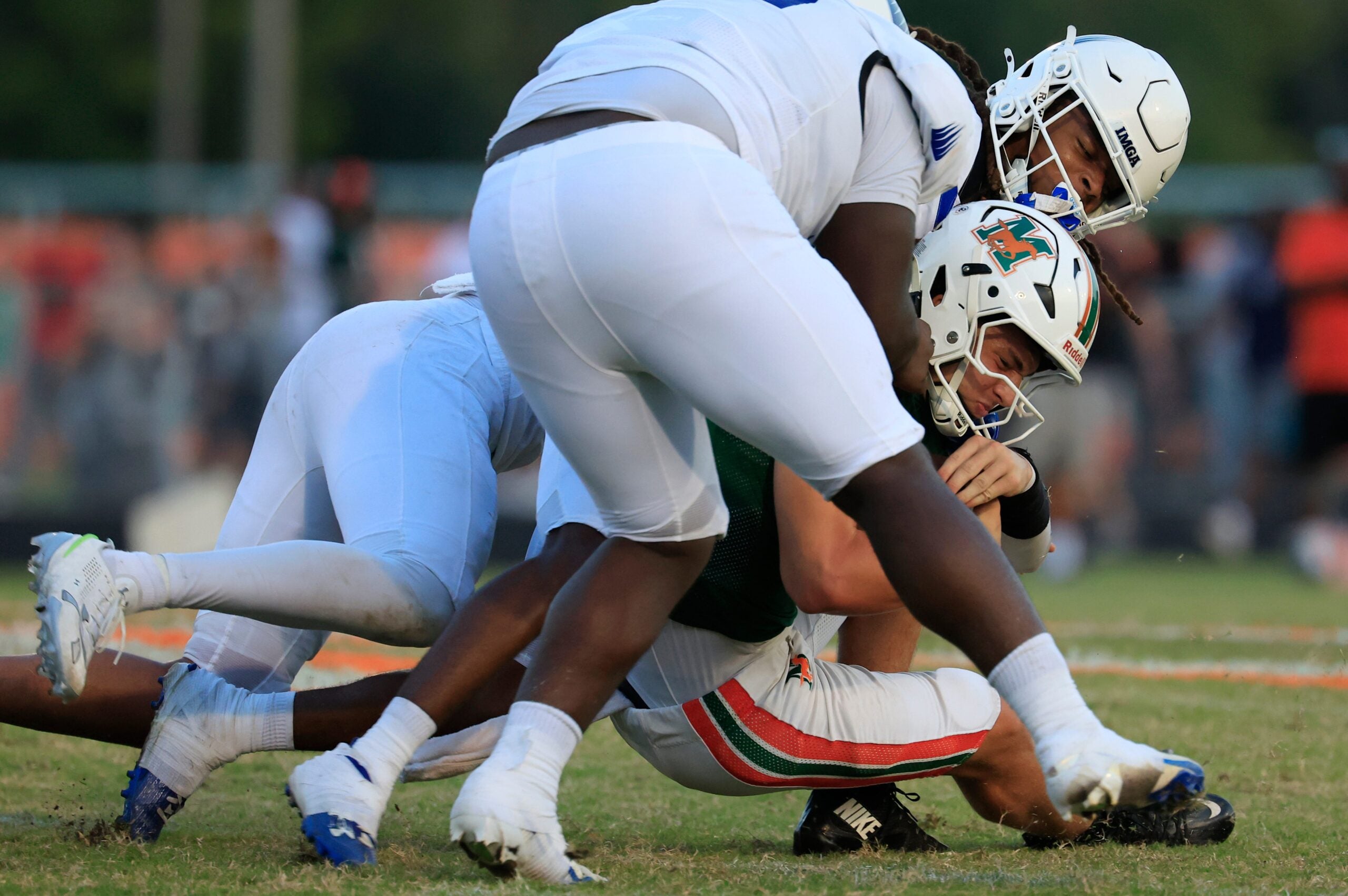 Mandarin's Knox Annis (8), center, is tackled by IMG Academy's Censere Gayloard (21), center back, along with Zyron Forstall (0), left, and Joseph Graves (75), top, during the second quarter of a high school football matchup at Mandarin High School, Friday, Sept. 19, 2025, in Jacksonville, Fla. The IMG Academy Ascenders defeated the Mandarin Mustangs 57-7.