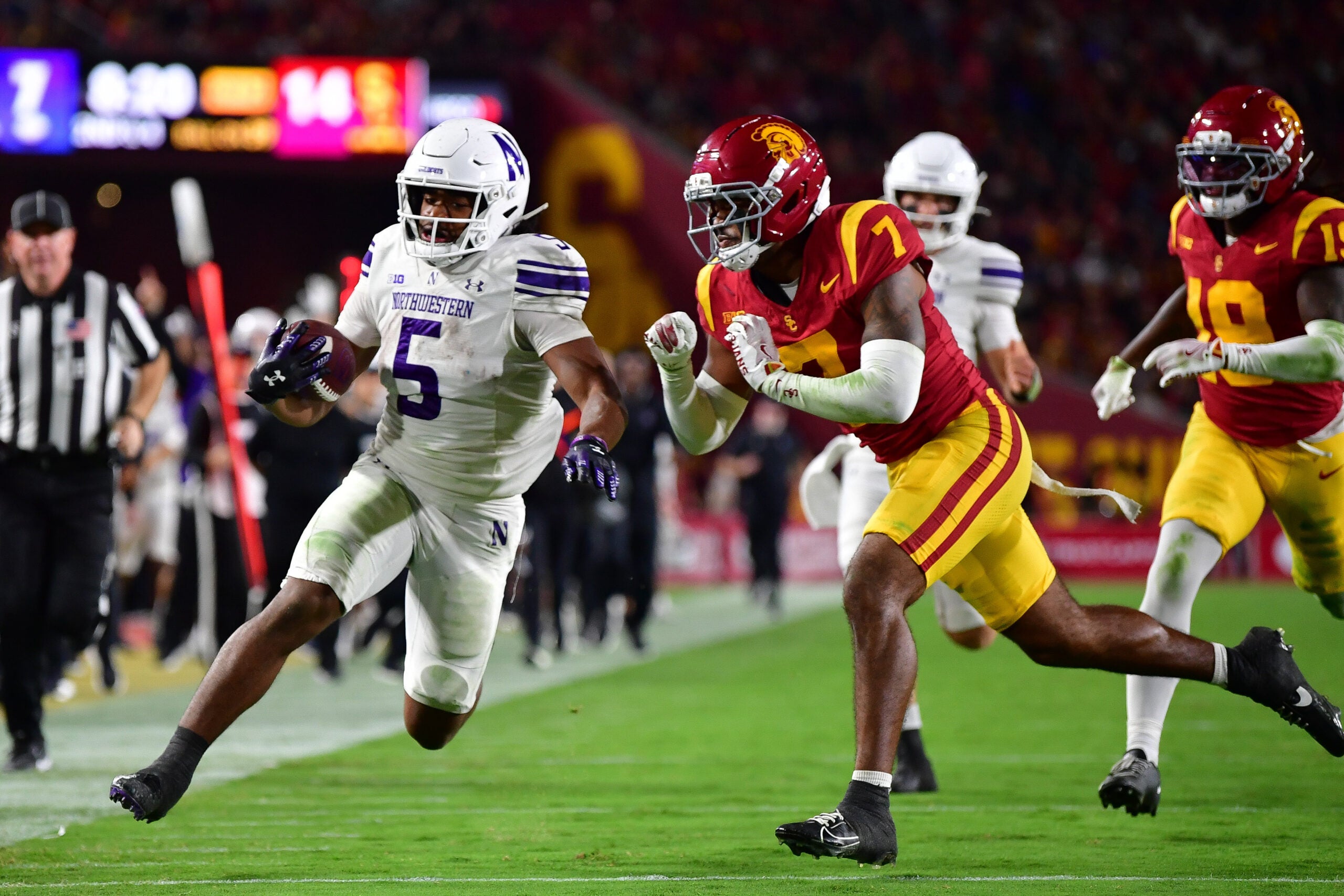 Nov 7, 2025; Los Angeles, California, USA; Northwestern Wildcats running back Caleb Komolafe (5) runs the ball against Southern California Trojans safety Kamari Ramsey (7) during the first half at the Los Angeles Memorial Coliseum.