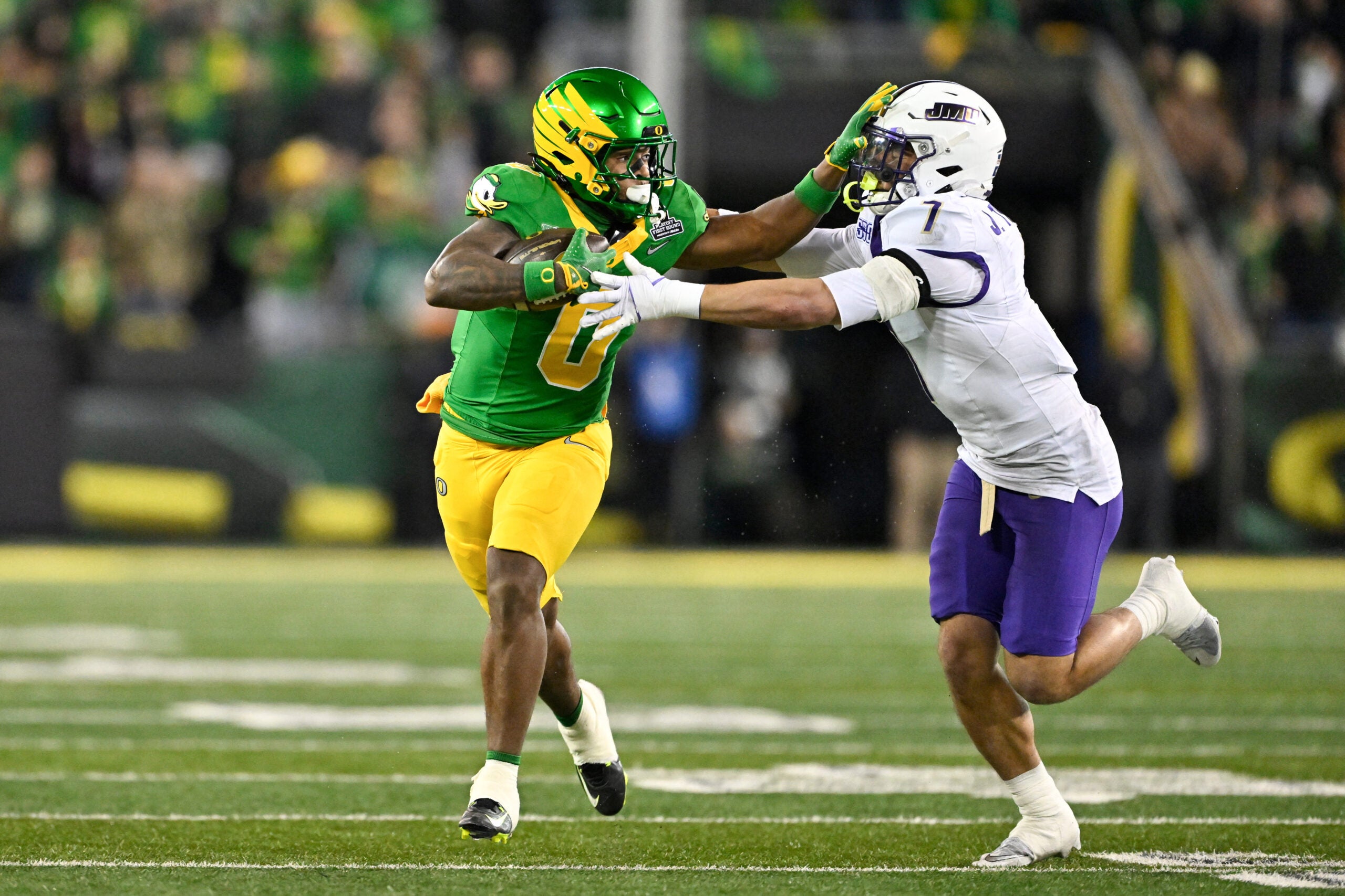 Dec 20, 2025; Eugene, OR, USA; Oregon Ducks running back Jordon Davison (0) rushes and stiff arms James Madison Dukes safety Jacob Thomas (7) during the second quarter at Autzen Stadium.