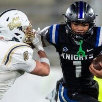 Montgomery Catholic's Kingston Preyear (1) stiff arms Moody’s Marshall Teofilo (6) during the Class 5A football state championship at Protective Stadium in Birmingham, Ala., on Thursday, Dec. 5, 2024. Montgomery Catholic leads Moody 14-0 at halftime.