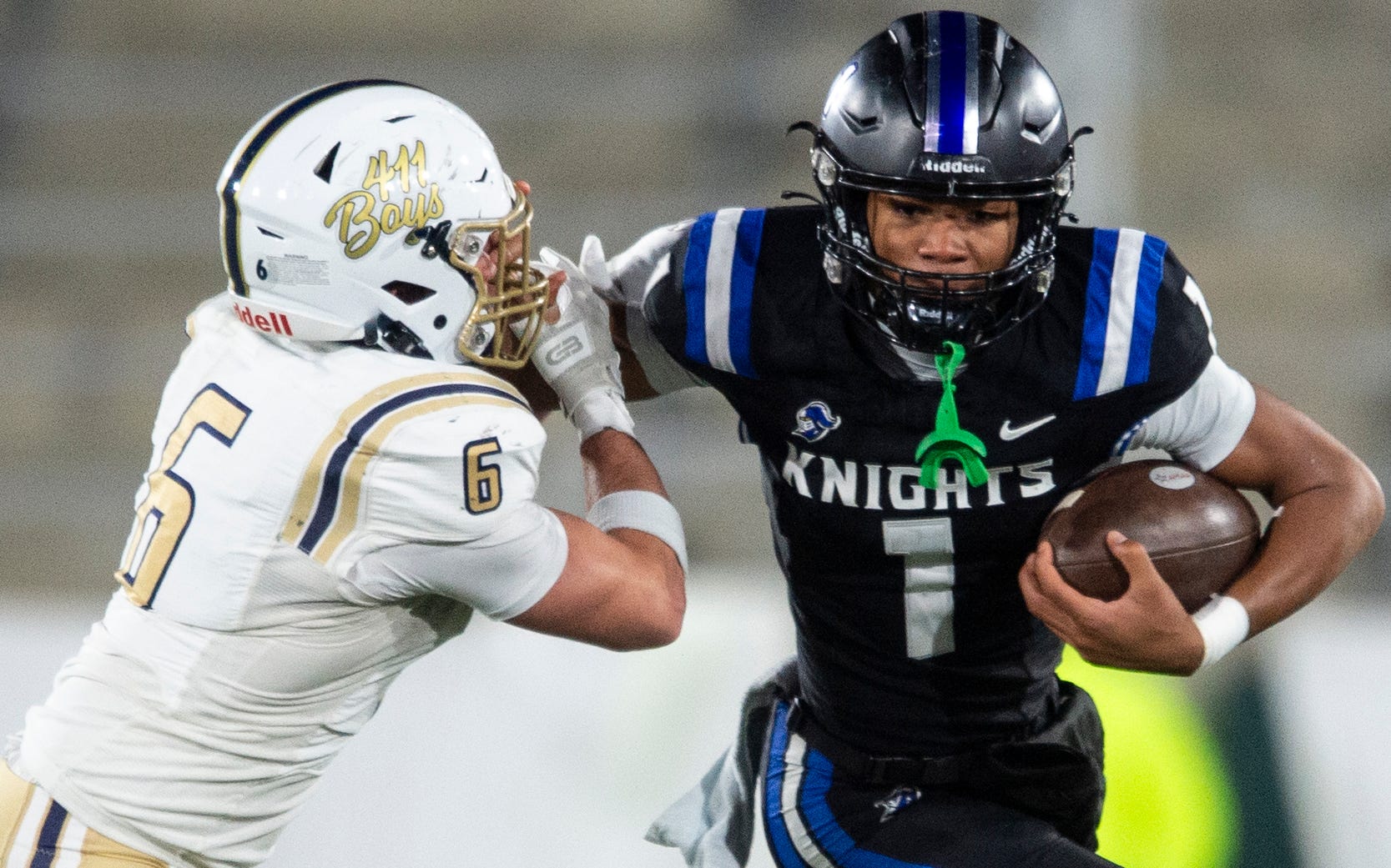 Montgomery Catholic's Kingston Preyear (1) stiff arms Moody’s Marshall Teofilo (6) during the Class 5A football state championship at Protective Stadium in Birmingham, Ala., on Thursday, Dec. 5, 2024. Montgomery Catholic leads Moody 14-0 at halftime.