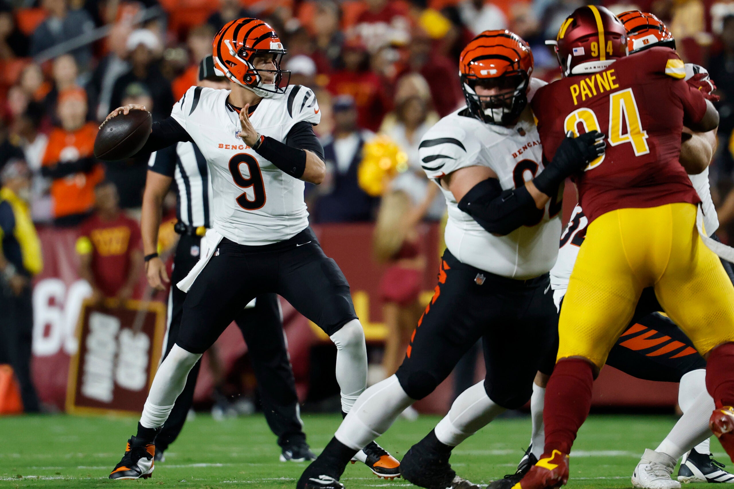 Aug 18, 2025; Landover, Maryland, USA; Cincinnati Bengals quarterback Joe Burrow (9) passes the ball as Washington Commanders defensive tackle Daron Payne (94) rushes during the first quarter at Northwest Stadium.