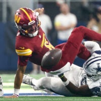 Oct 19, 2025; Arlington, Texas, USA; Washington Commanders quarterback Jayden Daniels (5) fumbles the ball defended by Dallas Cowboys linebacker Shemar James (50) during the third quarter of the game at AT&T Stadium.