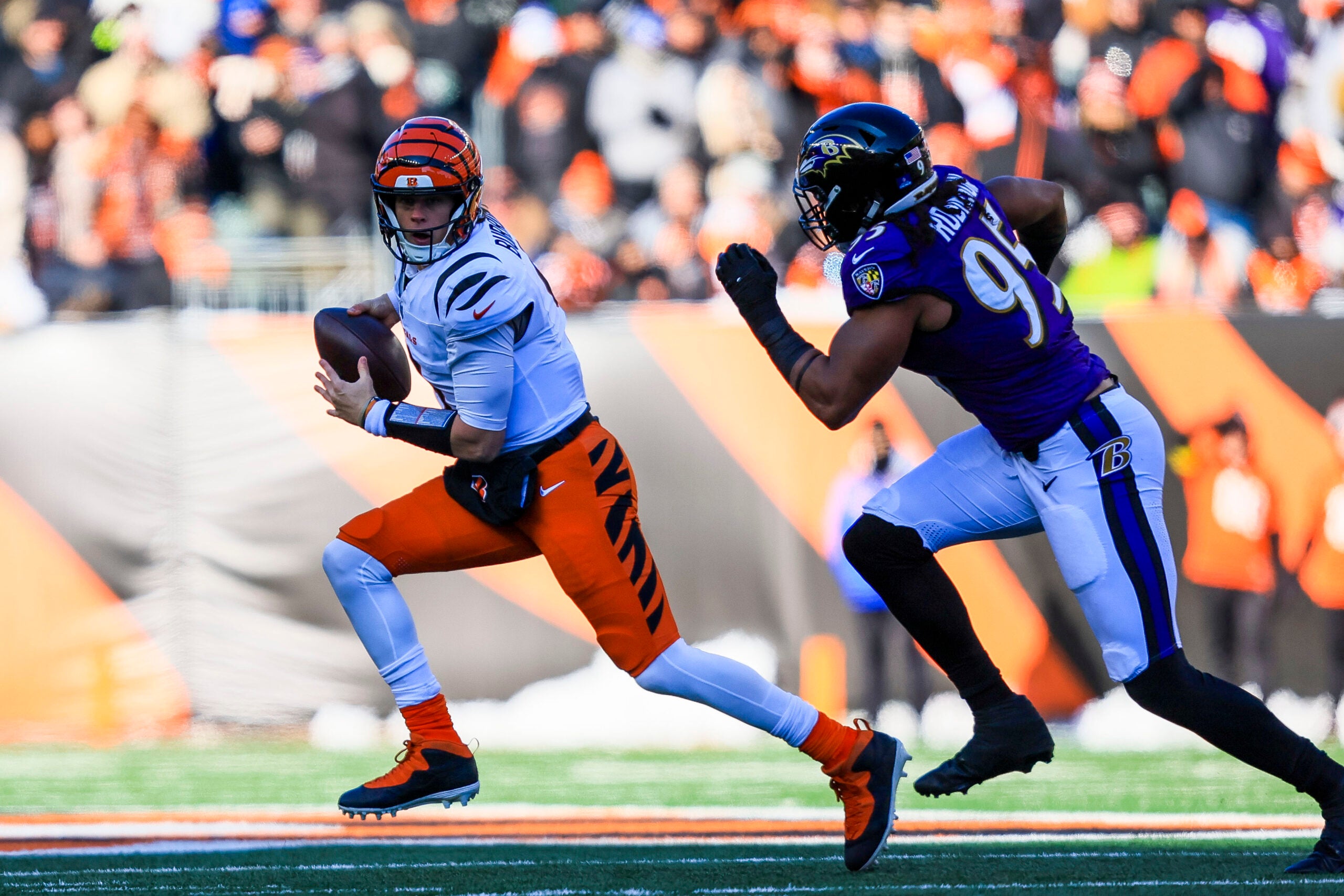 Dec 14, 2025; Cincinnati, Ohio, USA; Cincinnati Bengals quarterback Joe Burrow (9) runs with the ball against Baltimore Ravens linebacker Tavius Robinson (95) in the first half at Paycor Stadium.