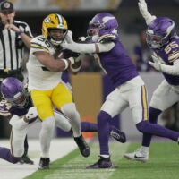 Jan 4, 2026; Minneapolis, Minnesota, USA; Green Bay Packers running back Chris Brooks (30) is shoved out of bounds by Minnesota Vikings safety Jay Ward (24) and cornerback Byron Murphy Jr. (7) during the second quarter at U.S. Bank Stadium.