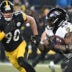 Jan 4, 2026; Pittsburgh, Pennsylvania, USA; Baltimore Ravens running back Derrick Henry (22) rushes the ball past Pittsburgh Steelers linebacker T.J. Watt (90) during the first half at Acrisure Stadium.