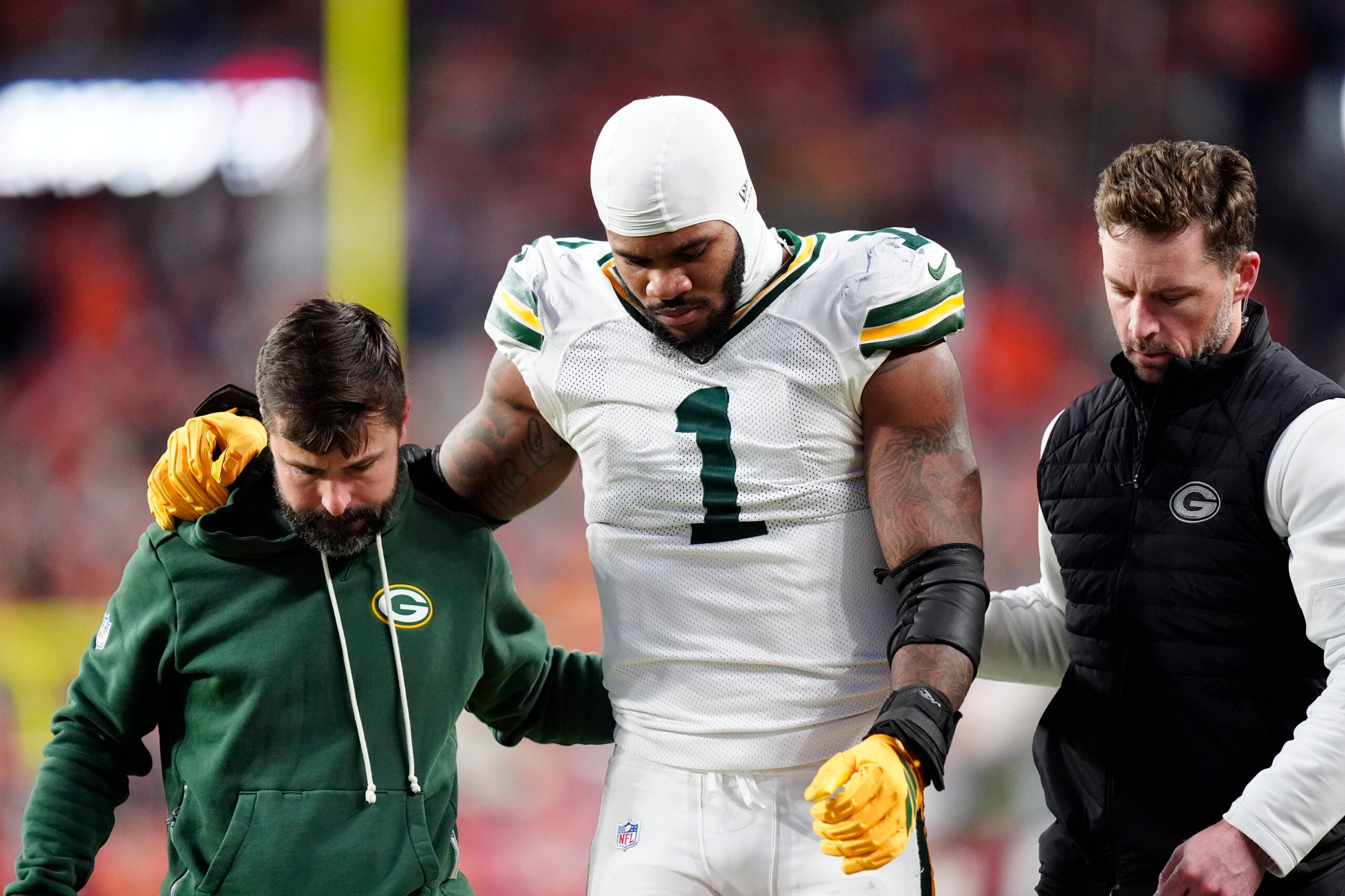 Dec 14, 2025; Denver, Colorado, USA; Green Bay Packers defensive end Micah Parsons (1) walks off the field with help from medical personnel following an injury during the third quarter against the Denver Broncos at Empower Field at Mile High.