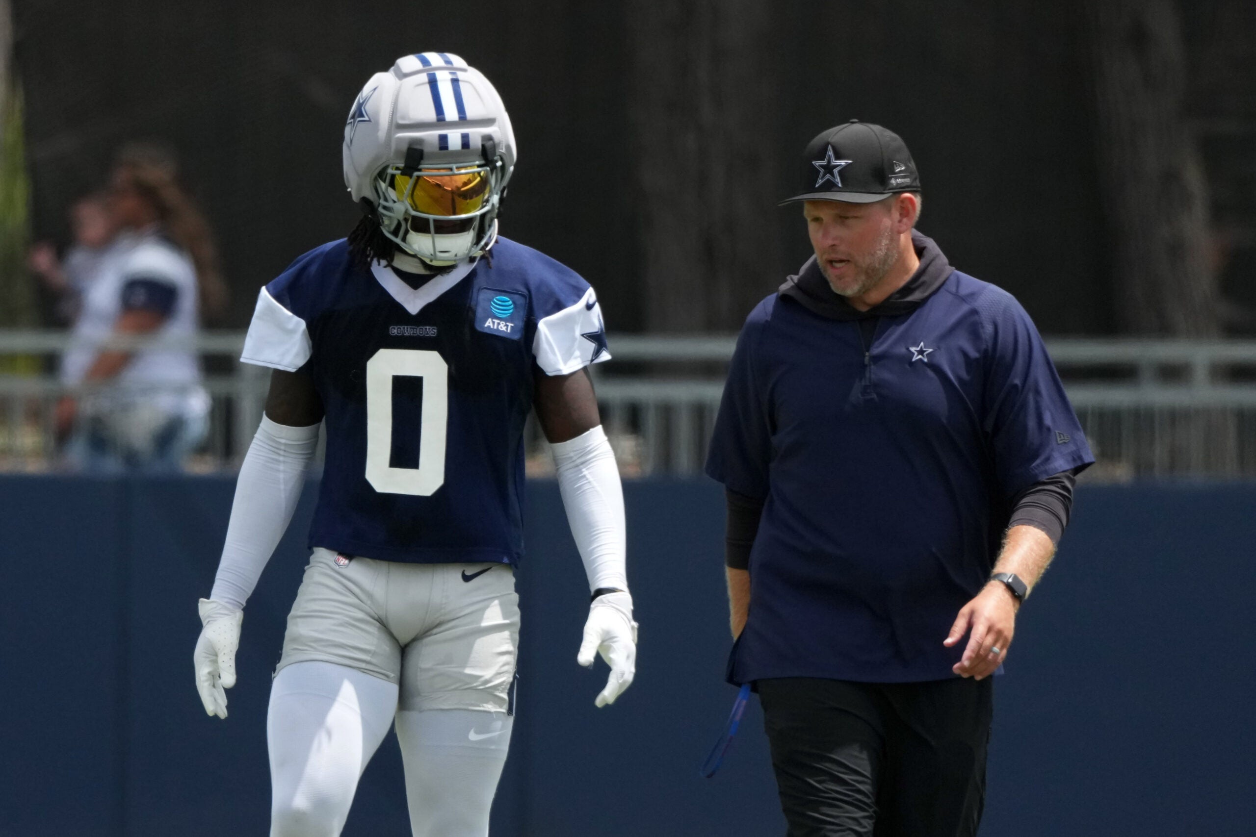 Jul 29, 2026; Oxnard, CA, USA; Dallas Cowboys linebacker DeMarvion Overshown (0) talks with inside linebackers coach Scott Symons at training camp at River Ridge Playing Fields.