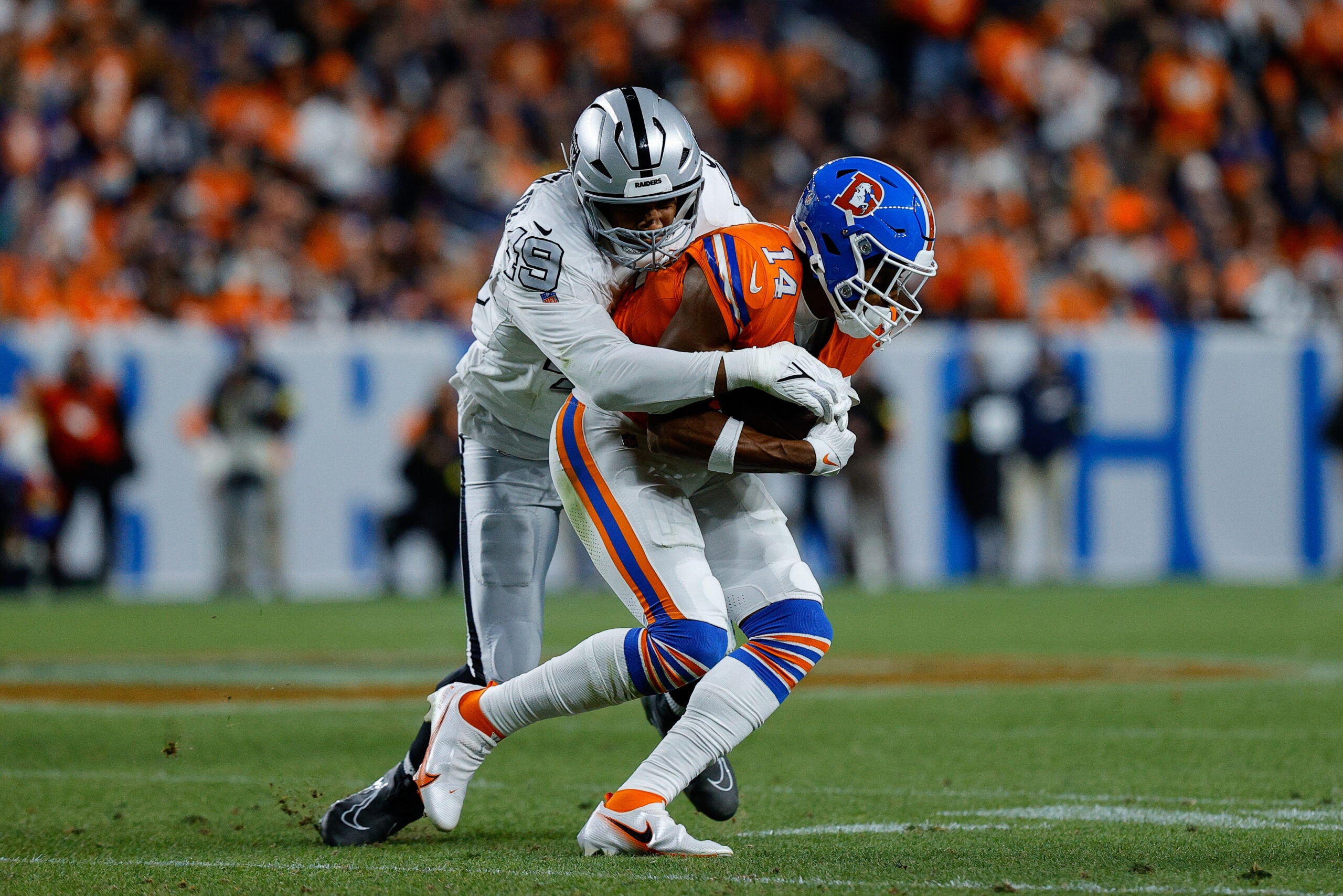 Nov 6, 2025; Denver, Colorado, USA; Denver Broncos wide receiver Courtland Sutton (14) is tackled by Las Vegas Raiders defensive end Charles Snowden (49) in the fourth quarter at Empower Field at Mile High.