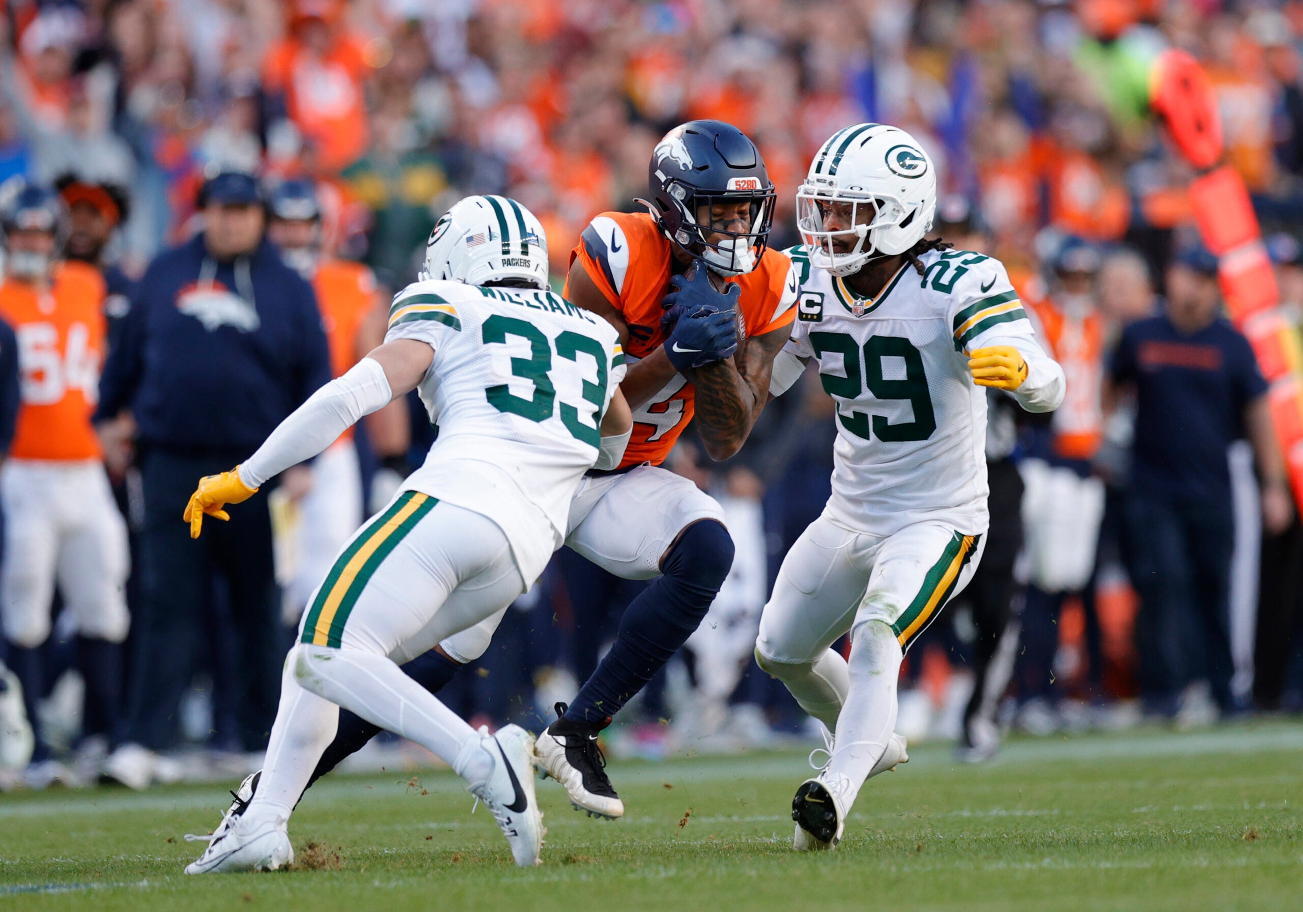 Dec 14, 2025; Denver, Colorado, USA; Denver Broncos wide receiver Courtland Sutton (14) runs for a gain past Green Bay Packers safety Evan Williams (33) and safety Xavier McKinney (29) during the second quarter at Empower Field at Mile High.