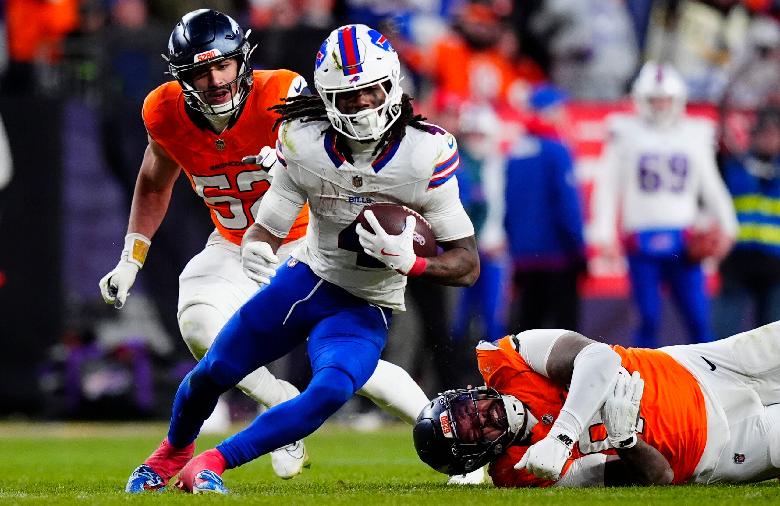 Jan 17, 2026; Denver, CO, USA; Buffalo Bills running back James Cook III (4) runs against Denver Broncos linebacker Jonah Elliss (52) and defensive end Eyioma Uwazurike (96) during the fourth quarter of an AFC Divisional Round playoff game at Empower Field at Mile High.