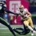 Jan 17, 2026; Seattle, WA, USA; San Francisco 49ers running back Christian McCaffrey (23) carries the ball as Seattle Seahawks cornerback Devon Witherspoon (21) defends during the first half in an NFC Divisional Round game at Lumen Field.