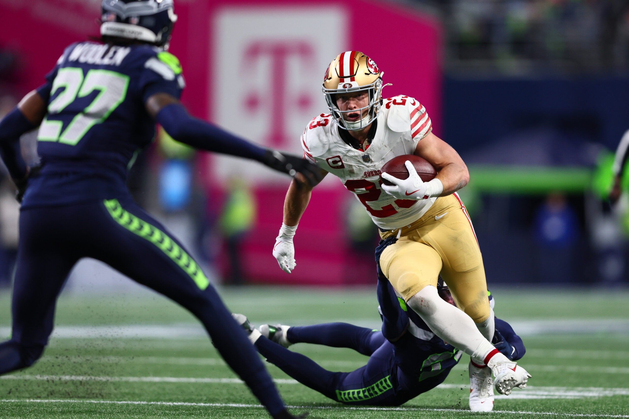 Jan 17, 2026; Seattle, WA, USA; San Francisco 49ers running back Christian McCaffrey (23) carries the ball as Seattle Seahawks cornerback Devon Witherspoon (21) defends during the first half in an NFC Divisional Round game at Lumen Field.