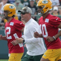Green Bay Packers quarterbacks coach Luke Getsy runs between quarterback Aaron Rodgers (12) and quarterback Jordan Love (10) during the second day of training camp Thursday, July 29, 2021 in Green Bay, Wis.