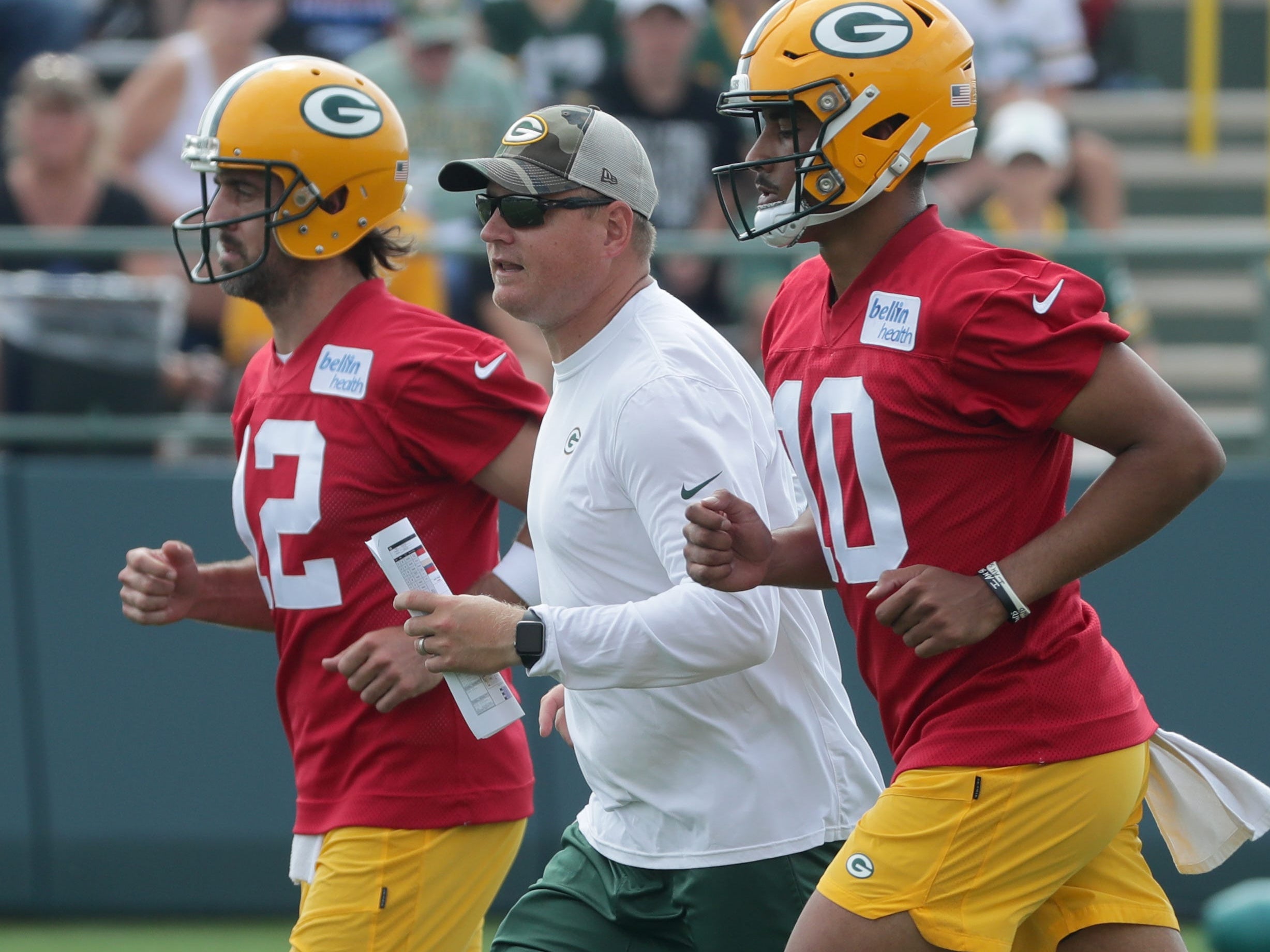 Green Bay Packers quarterbacks coach Luke Getsy runs between quarterback Aaron Rodgers (12) and quarterback Jordan Love (10) during the second day of training camp Thursday, July 29, 2021 in Green Bay, Wis.