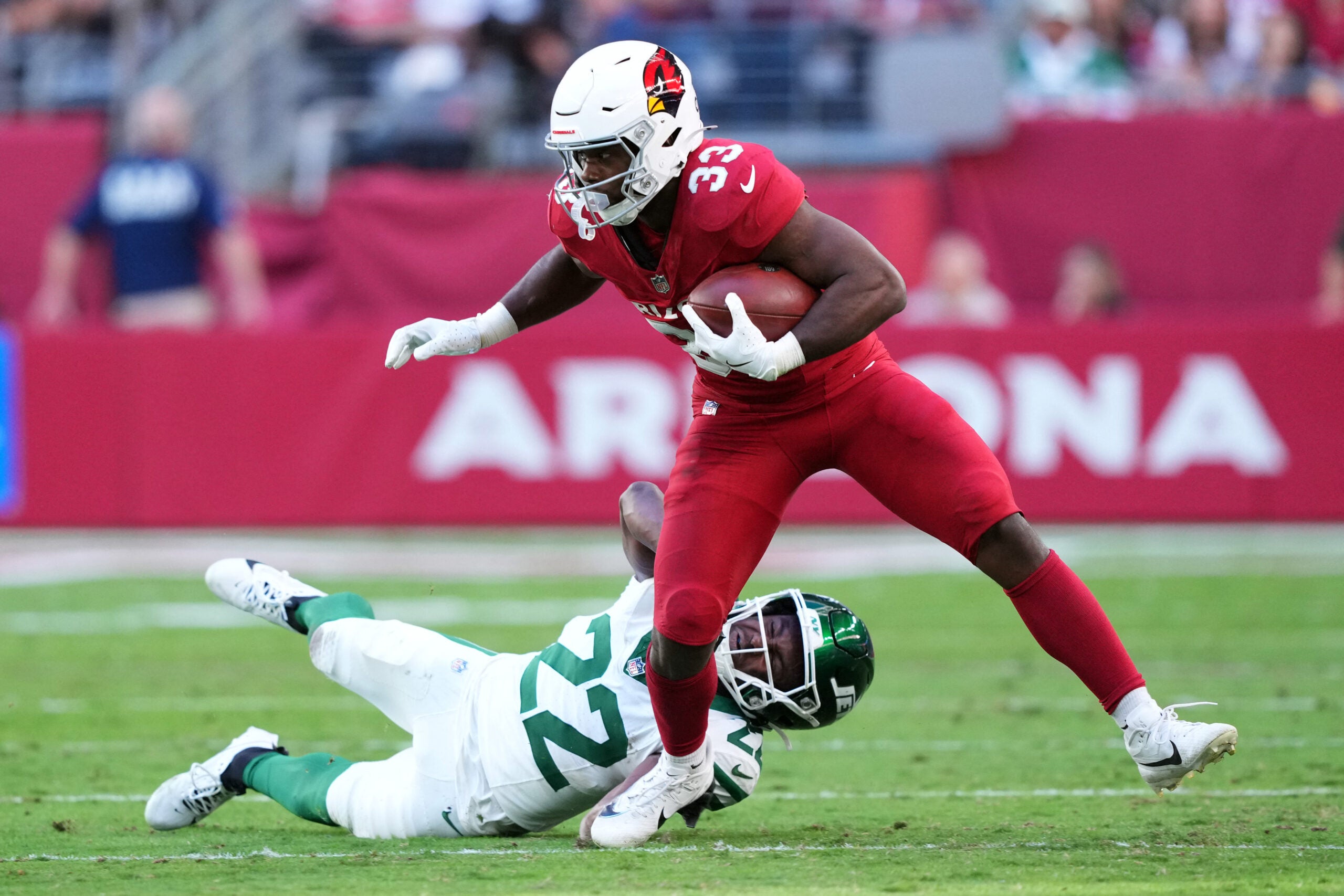 Nov 10, 2024; Glendale, Arizona, USA; Arizona Cardinals running back Trey Benson (33) runs by New York Jets safety Tony Adams (22) during the first half at State Farm Stadium.