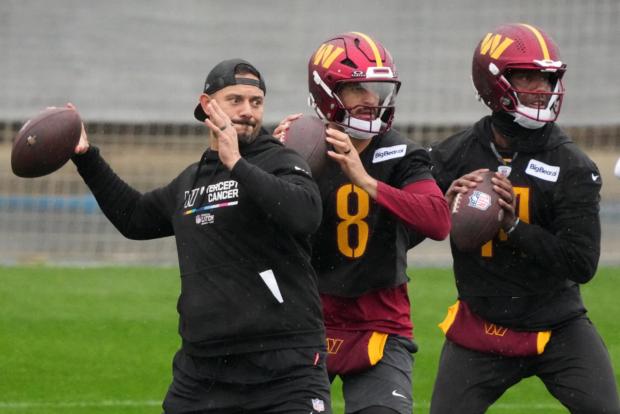 Nov 13, 2025; Madrid, Spain; Washington Commanders assistant quarterbacks coach David Blough (left) and quarterbacks Marcus Mariota (8) and Josh Johnson (14) throw the ball during practice at Ciudad Deportiva del Real Madrid.
