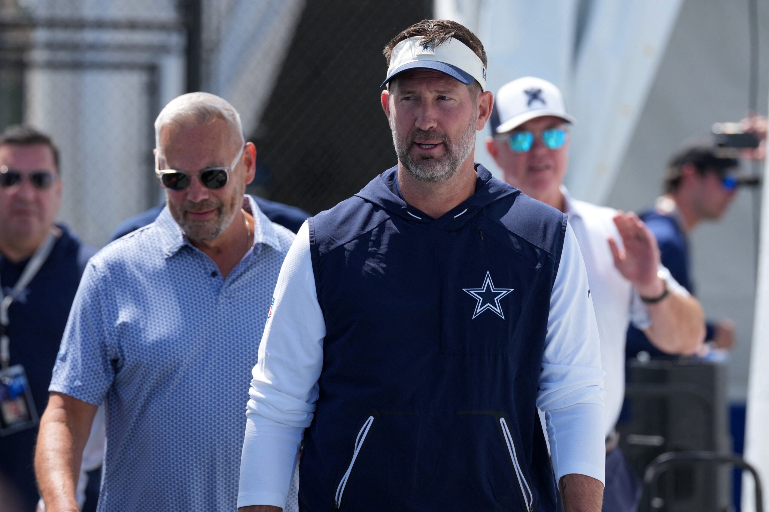 Jul 28, 2026; Oxnard, CA, USA; Dallas Cowboys coach Brian Schottenheimer walks with vice president of public relations and communications Tad Carper at training camp opening press conference at River Ridge Playing Fields.