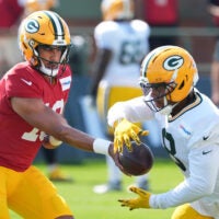 Green Bay Packers quarterback Jordan Love (10) hands off the ball to running back Josh Jacobs (8) during the fifth day of training camp on Aug. 3, 2026, at Ray Nitschke Field in Ashwaubenon, Wis.