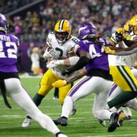 Dec 29, 2024; Minneapolis, Minnesota, USA; Green Bay Packers running back Josh Jacobs (8) looks for room to run against Minnesota Vikings safety Josh Metellus (44) during their football game at U.S. Bank Stadium.