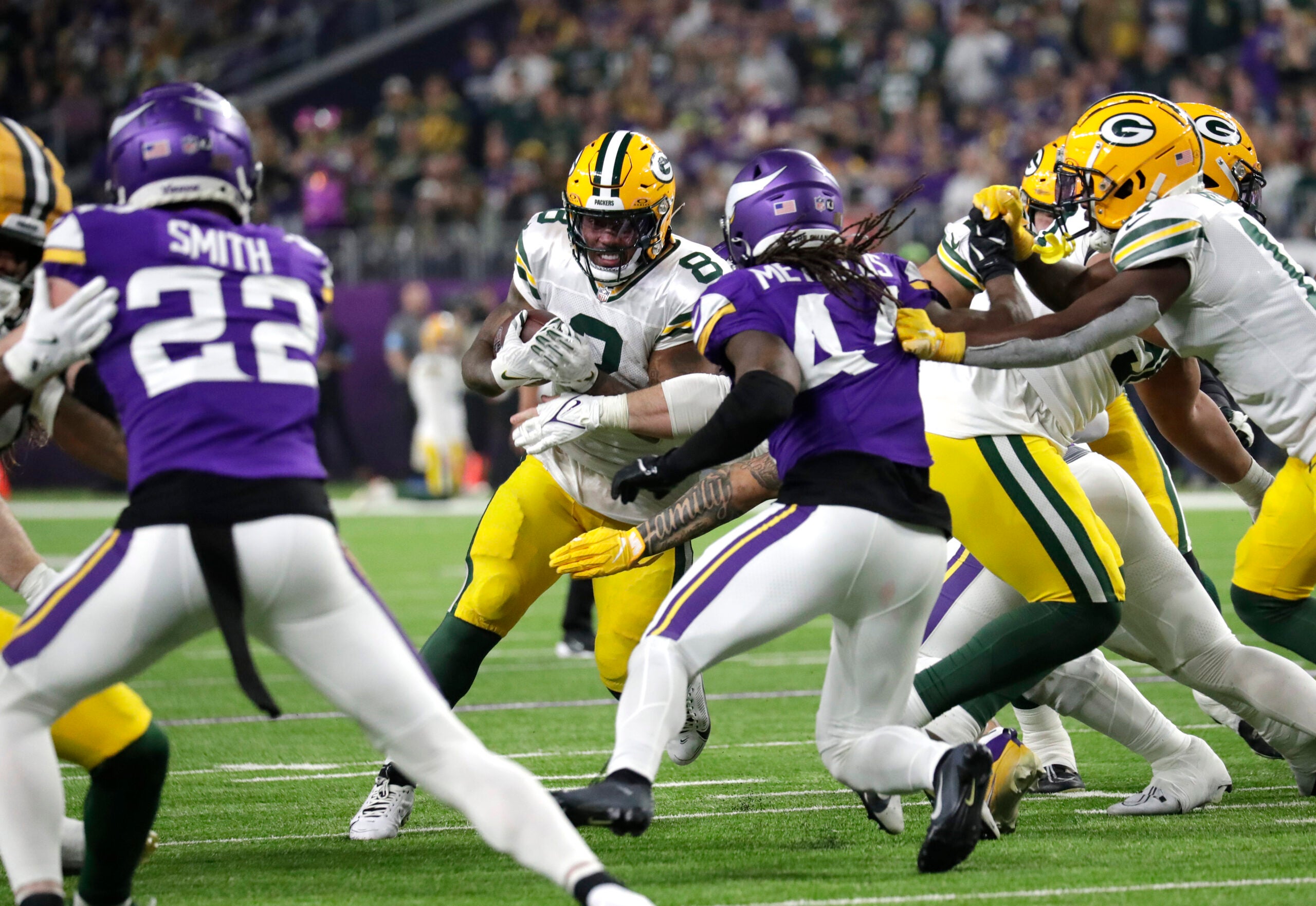 Dec 29, 2024; Minneapolis, Minnesota, USA; Green Bay Packers running back Josh Jacobs (8) looks for room to run against Minnesota Vikings safety Josh Metellus (44) during their football game at U.S. Bank Stadium.