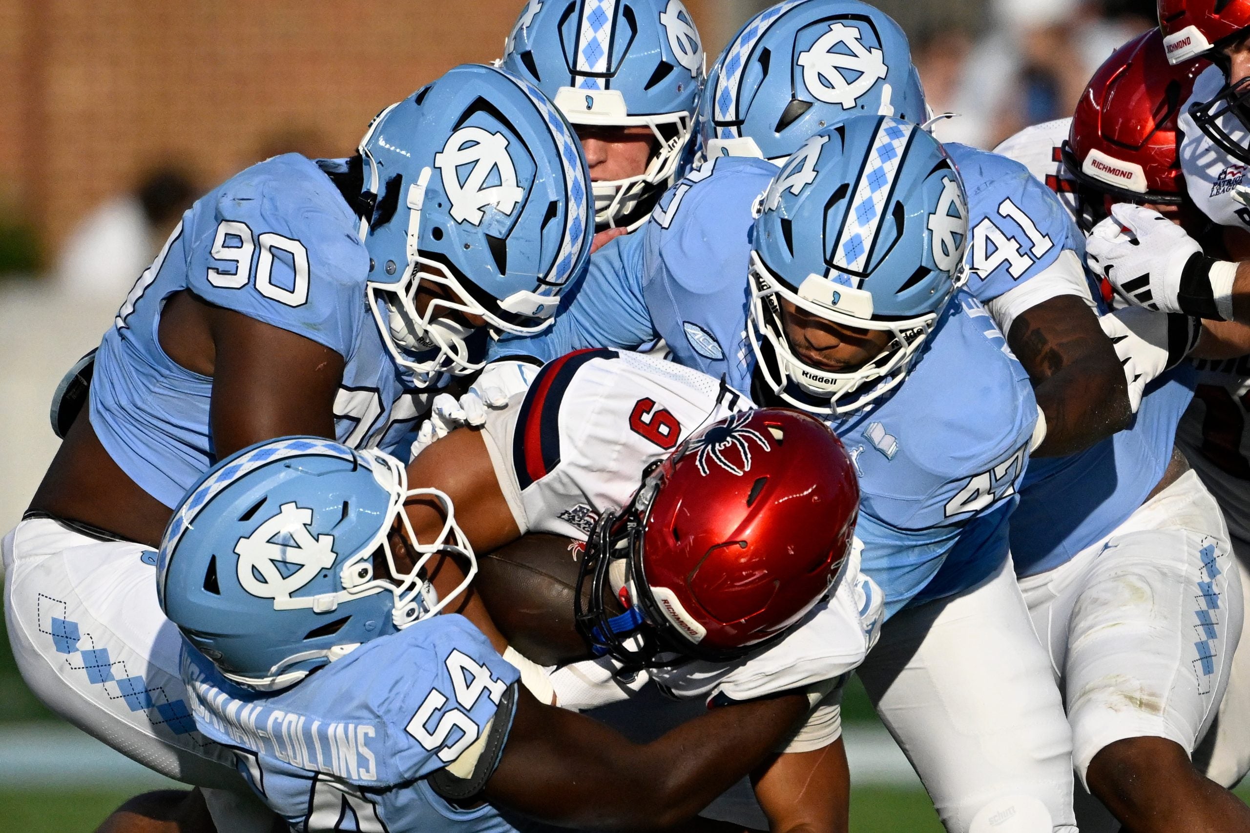 Sep 13, 2025; Chapel Hill, North Carolina, USA; North Carolina Tar Heels defensive lineman Xavier Lewis (90) and linebackers Timir Hickman-Collins (54) and Austin Alexander (47) tackle Richmond Spiders running back Michael Creamer (9) in the fourth quarter at Kenan Stadium.