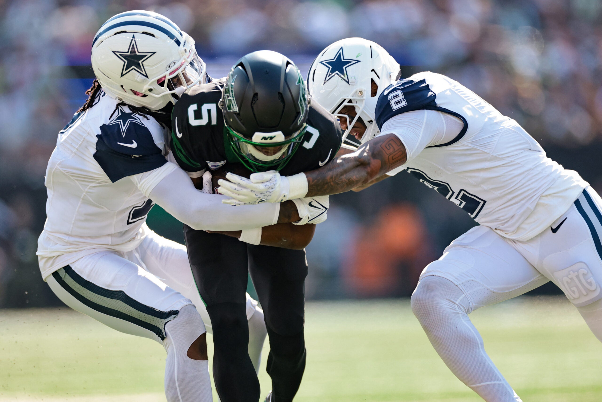 Oct 5, 2025; East Rutherford, New Jersey, USA; New York Jets wide receiver Garrett Wilson (5) is tackled by Dallas Cowboys cornerback Trevon Diggs (7) and safety Juanyeh Thomas (2) during the first half at MetLife Stadium.