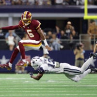 Sep 20, 2026; Arlington, Texas, USA; Washington Commanders quarterback Jayden Daniels (5) leaps to avoid a tackle by Dallas Cowboys safety Caleb Downs (13) while running with the ball during the second half at AT&T Stadium.
