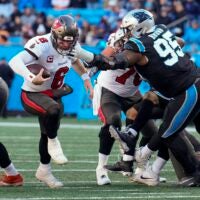 Jan 7, 2024; Charlotte, North Carolina, USA; Tampa Bay Buccaneers quarterback Baker Mayfield (6) keeps the ball and runs with Carolina Panthers defensive tackle Derrick Brown (95) reaching out for the attempted stop during the second half at Bank of America Stadium.