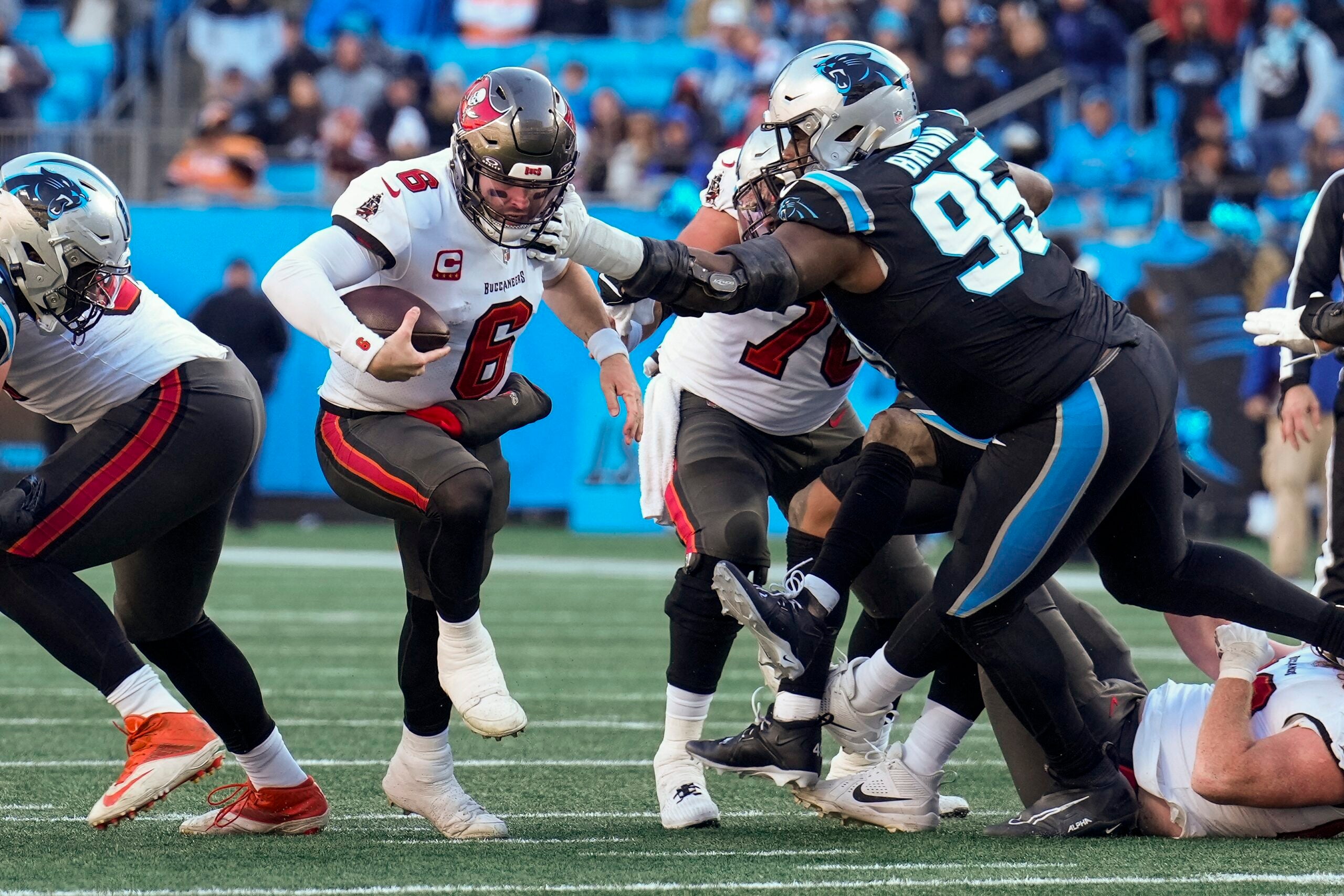 Jan 7, 2024; Charlotte, North Carolina, USA; Tampa Bay Buccaneers quarterback Baker Mayfield (6) keeps the ball and runs with Carolina Panthers defensive tackle Derrick Brown (95) reaching out for the attempted stop during the second half at Bank of America Stadium.
