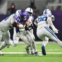 Nov 3, 2024; Minneapolis, Minnesota, USA; Minnesota Vikings quarterback Sam Darnold (14) is tackled by Indianapolis Colts defensive tackle Grover Stewart (90) and defensive tackle DeForest Buckner (99) during the second quarter at U.S. Bank Stadium.