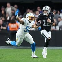 Jan 5, 2025; Paradise, Nevada, USA; Las Vegas Raiders quarterback Aidan O'Connell (12) carries the ball against Los Angeles Chargers linebacker Khalil Mack (52) in the second half at Allegiant Stadium.