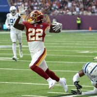 Oct 4, 2026; Tottenham, ENG; Washington Commanders running back Jacory Croskey-Merritt (22) runs with the ball against Indianapolis Colts linebacker Jaylon Carlies (57) during the first quarter at Tottenham Hotspur Stadium.