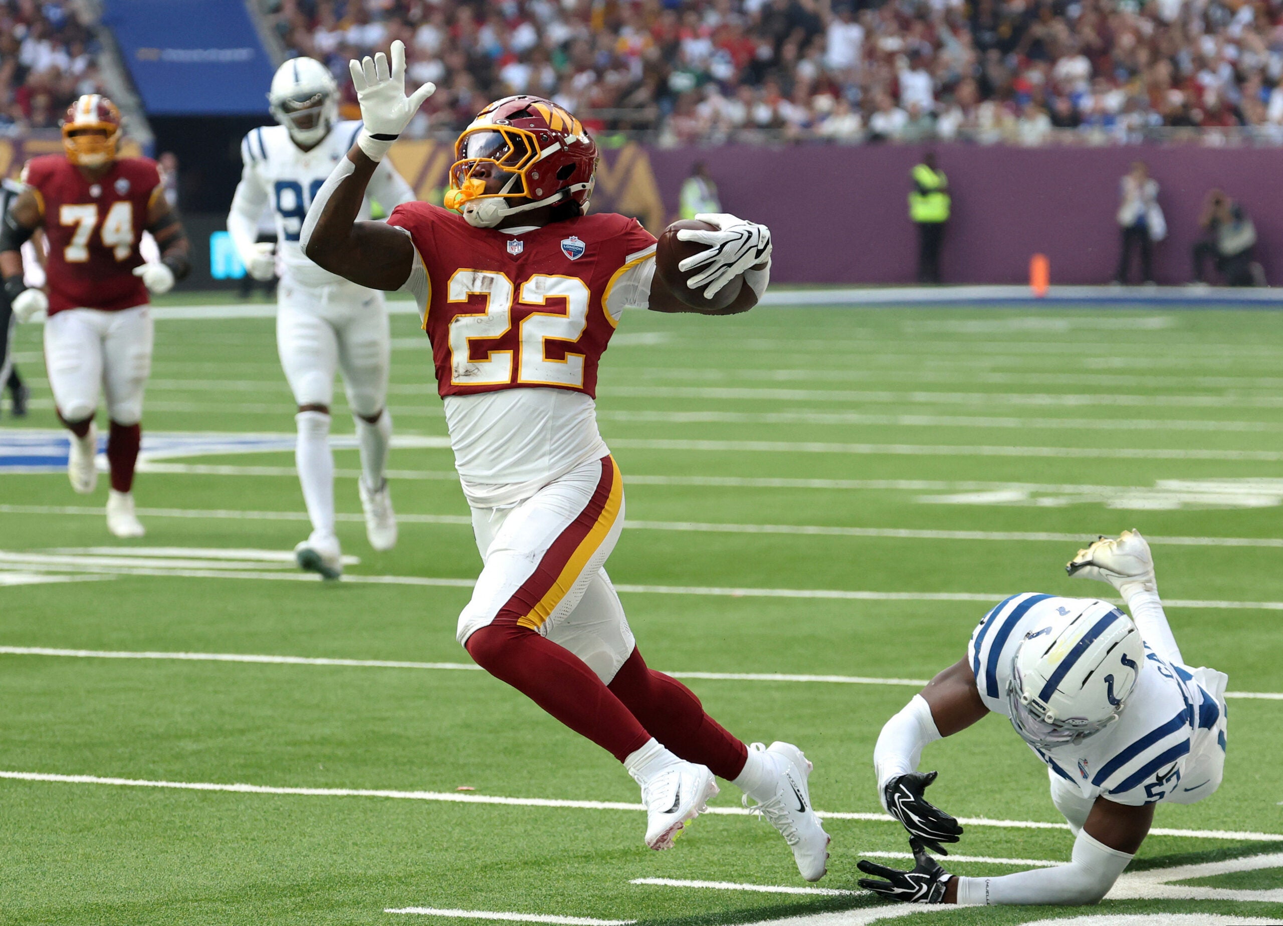 Oct 4, 2026; Tottenham, ENG; Washington Commanders running back Jacory Croskey-Merritt (22) runs with the ball against Indianapolis Colts linebacker Jaylon Carlies (57) during the first quarter at Tottenham Hotspur Stadium.