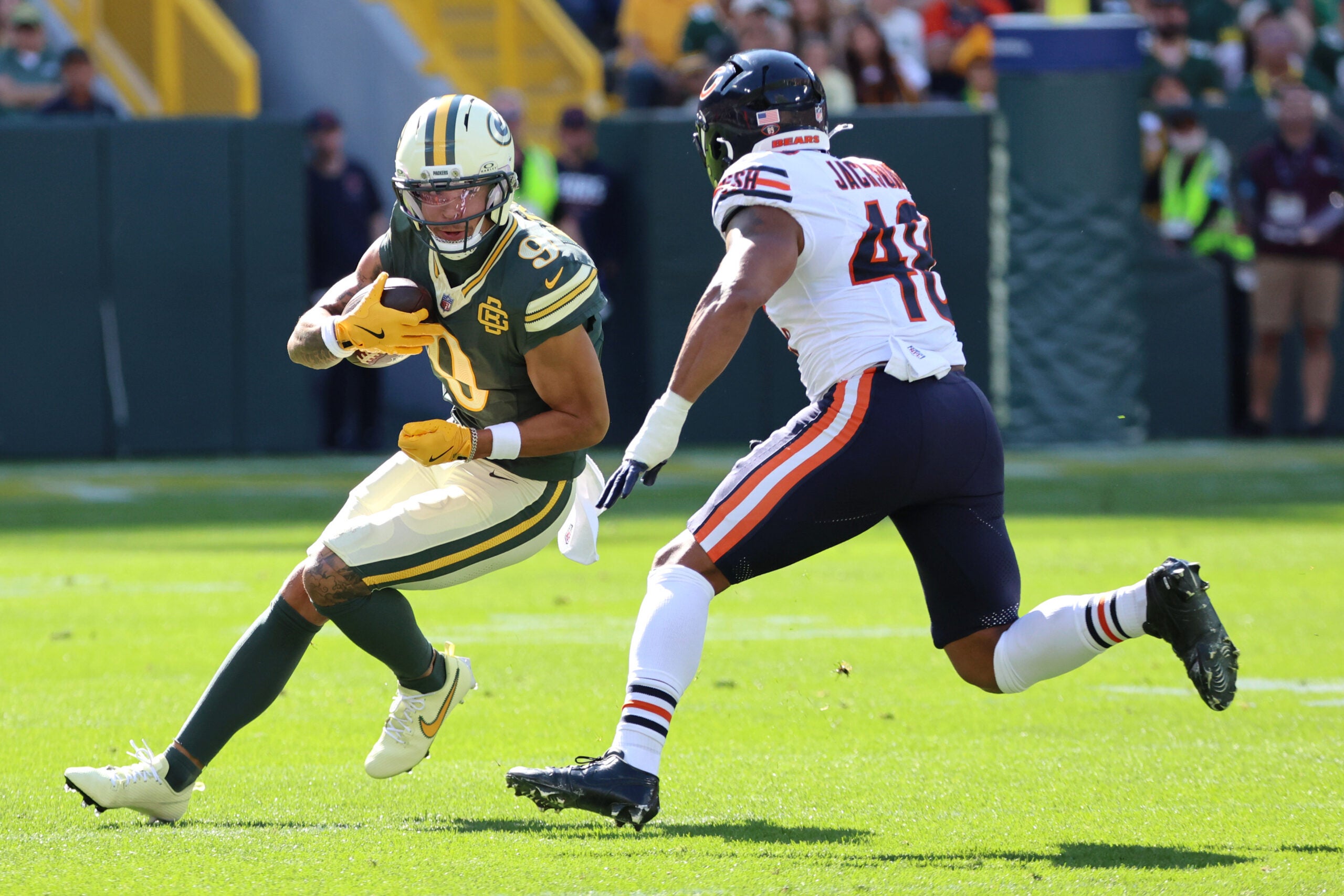 Oct 11, 2026; Green Bay, Wisconsin, USA; Green Bay Packers wide receiver Christian Watson (9) carries the ball defended by Chicago Bears linebacker D'Marco Jackson (48) during the first quarter at Lambeau Field.